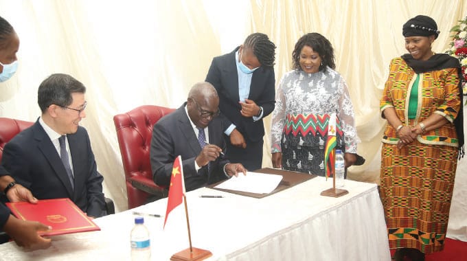 First Lady Amai Mnangagwa and Minister of Defence and War Veterans Affairs Oppah Muchinguri-Kashiri look on while Local Government and Public Works Minister July Moyo and Chinese Ambassador to Zimbabwe Guo Shaochun (left) sign the certificates at the State House in Harare yesterday.