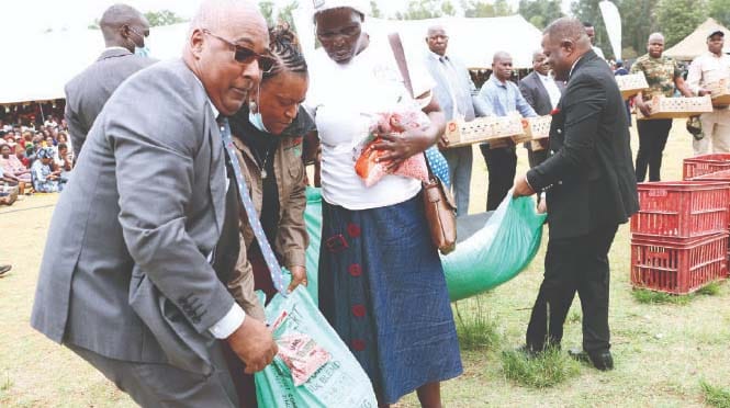 African Ambassadors accredited to Zimbabwe Mr Niklaa Kandijii of Namibia and Malawian Ambassador Mr Mwayiwayo Polepole assist in handing over fertilisers and seeds to women after the launch of Urban Transformation Programme by First Lady Dr Auxillia Mnangagwa in Dzivaresekwa, Harare on Monday