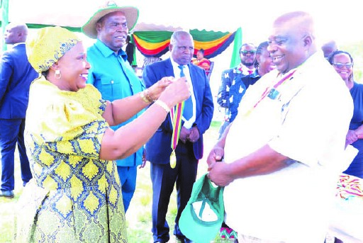 Environment patron First Lady Dr Auxillia Mnangagwa hands over a second medal to one of the war veterans who scooped prizes during the capacity building programme in agriculture and environmental management for liberation war fighters and youths in Hurungwe yesterday