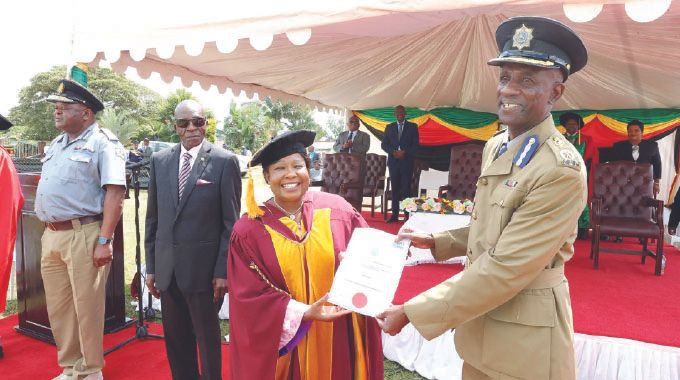 First Lady Dr Auxillia Mnangagwa hands over a certificate of appreciation to Zimbabwe Republic Police Staff College principal Assistant Commissioner Edward Tshuma during the graduation of beneficiaries of her Angel of Hope Foundation partnership in short courses with ZOU at ZRP Staff College in Harare yesterday