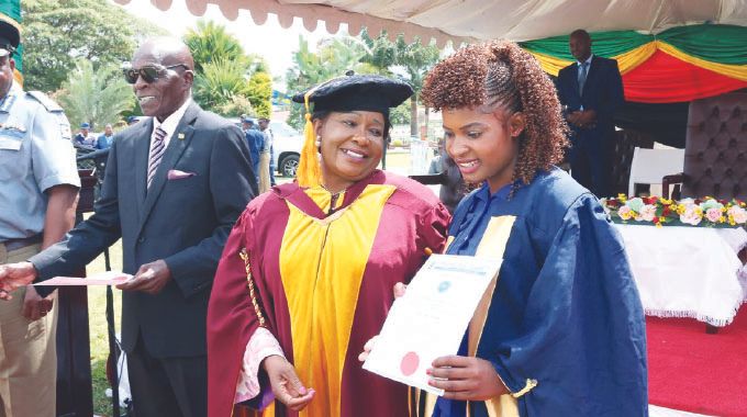 Angel of Hope Foundation patron First Lady Dr Auxillia Mnangagwa hands over a certificate to one of the beneficiaries of her organisation’s partnership in short courses with Zimbabwe Open University at ZRP Staff College in Harare yesterday