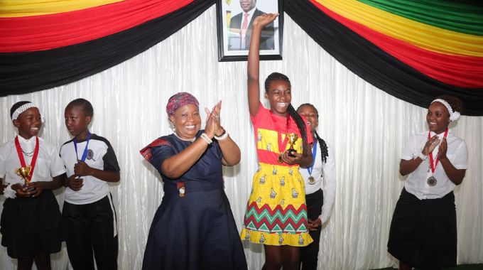 First Lady Dr Auxillia Mnangagwa celebrates and congratulates Lisa Ganyani who came out tops in the poem competition while other contestants look on during a boot camp yesterday