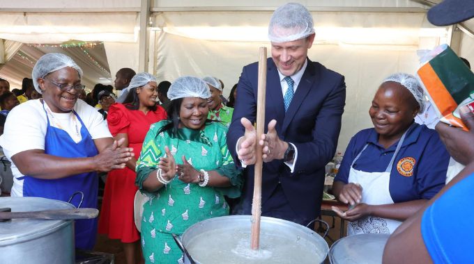 First Lady Dr Auxillia Mnangagwa, Ethiopian, British and Ghanaian Ambassadors to Zimbabwe respectively Mr Rashid Homammed, Mr Pete Vowles and Mr Alexander Ntrakwa serve food to guests in her traditional kitchen at the 64th ZITF in Bulawayo