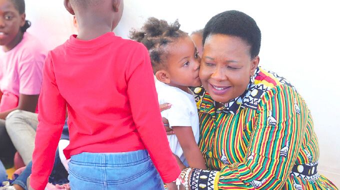 First Lady Dr Auxillia Mnangagwa is kissed by a girl during her interactive session with children who attended the Farm to Market and Arts festival she organised and launched in Harare. – Pictures: John Manzongo