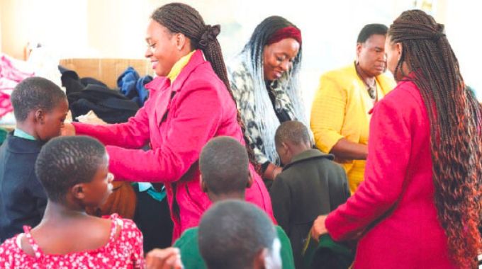 Mrs Marian Udemba and her twin daughters assist Hupenyu Hutsva Children’s Home acting superintendent Mrs Anesu Chitoro to distribute winter coats they donated to Angel of Hope Foundation to the children at the home yesterday.