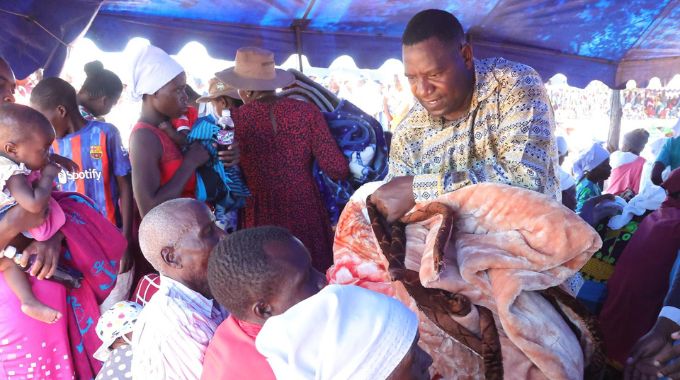 Mashonaland Central Minister of State and Devolution Christopher Magomo assists First Lady Dr Auxillia Mnangagwa in distributing blankets and food hampers she donated to the elderly, those living with disabilities, child headed families and other vulnerable groups in Muzarabani yesterday.