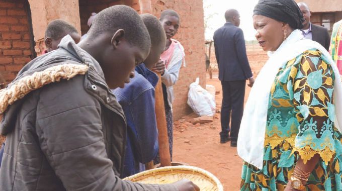 First Lady Dr Auxillia Mnangagwa interacts with girls as they prepared and winnow traditional grains during a nhanga programme she organised in Chingwizi on Tuesday