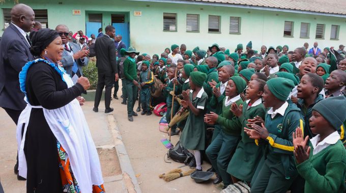 First Lady Dr Auxillia Mnangagwa is welcomed by learners, while Minister of Primary and Secondary Education Dr Torerayi Moyo looks on during her school feeding programme in Epworth on Friday