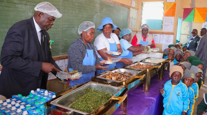 Primary and Secondary Education Minister Dr Torerayi Moyo serves food to learners during a school feeding programme organised by First Lady Dr Auxillia Mnangagwa in Epworth on Friday