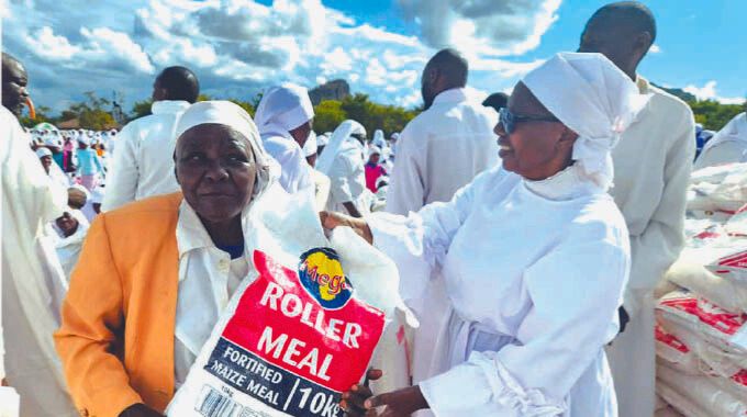 Minister of Veterans of the Liberations Struggle Affairs Monica Mavhunga hands over mealie meal to Vapositori veAfrica (Mwazha Apostolic Church) congregants on behalf of First Lady Dr Auxillia Mnangagwa, as they celebrated Apostle Paul Mwazha’s 106th birthday in Chiweshe on Saturday