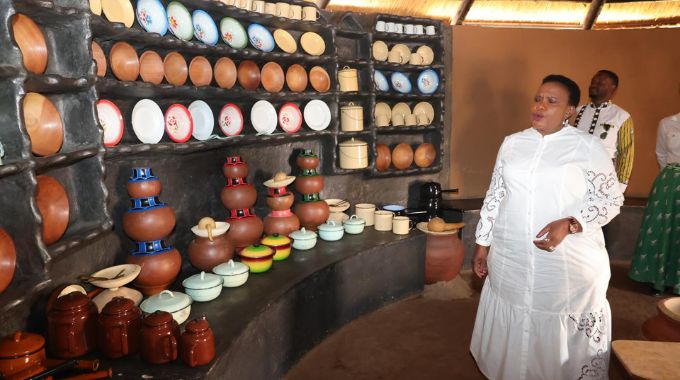 Culture and heritage patron, First Lady Dr Auxillia Mnangagwa looks at traditional and modern kitchen utensils such as clay pots and wooden plates in a Shona kitchen during her tour of the Heritage Village in Harare yesterday