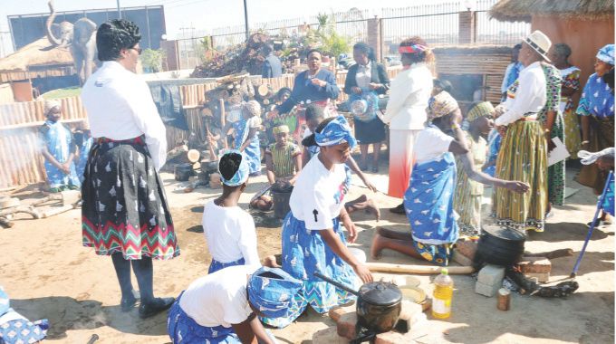 Girls perform traditional chores such as preparing traditional dishes under the watchful eye of First Lady Dr Auxillia Mnangagwa during a nhanga programme held for the first time at the Heritage Village in Harare on Sunday