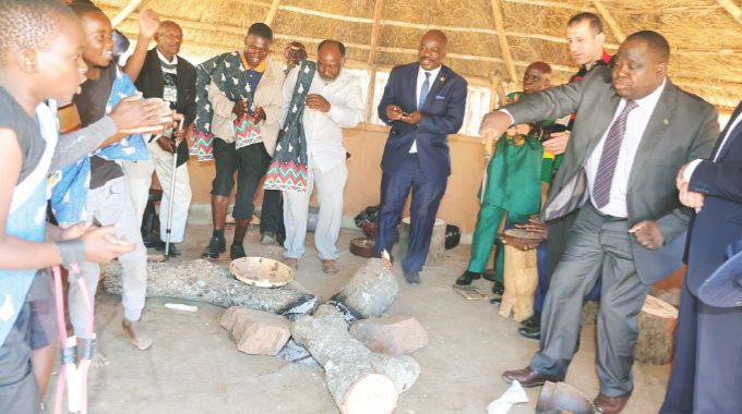 Zambia’s Ambassador to Zimbabwe Mr Derick Livune join boys and their elders in singing Zimbabwean traditional hunting songs, while holding a spear during a gota programme organised by First Lady Dr Auxillia Mnangagwa at the Heritage Village on Sunday