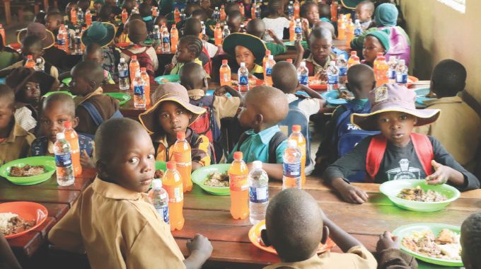 Schoolchildren enjoy their meal which was prepared and served by Health Ambassador First Lady Dr Auxillia Mnangagwa during the school feeding programme in Mashonaland East yesterday