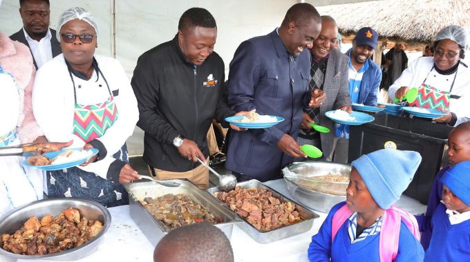 Minister of State for Provincial Affairs and Devolution for Midlands Owen Ncube and Mr Collins Mnangagwa serve food to learners during a school feeding programme organised by First Lady Dr Auxillia Mnangagwa