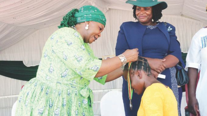 First Lady Dr Auxillia Mnangagwa awards a medal to one of the winners of the 2023/2024 farming season in Mashonaland Central yesterday