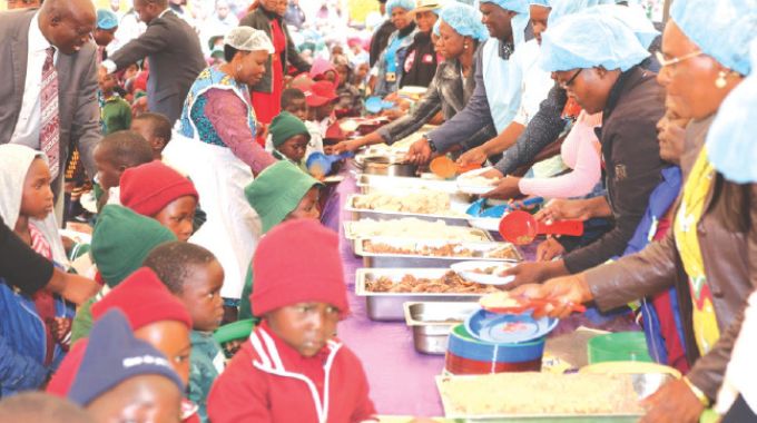 Schoolchildren receive food during a school feeding programme organised by First Lady Dr Auxillia Mnangagwa in Masvingo yesterday