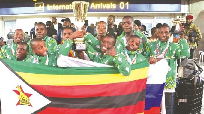 Children from Dr Auxillia Mnangagwa Children’s Home in Chiredzi who took part in the Brics+ International Sports, Arts and Culture Festival in Russia proudly display the Zimbabwean and Russian flags, their soccer trophies and medals upon their arrival at the Robert Gabriel Mugabe international Airport on Friday. — Pictures: John Manzongo