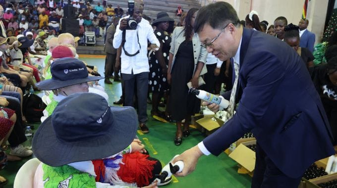 Chinese Ambassador to Zimbabwe Zhou Ding hands over sunscreen lotions and lip care to people with albinism in Chitungwiza yesterday.