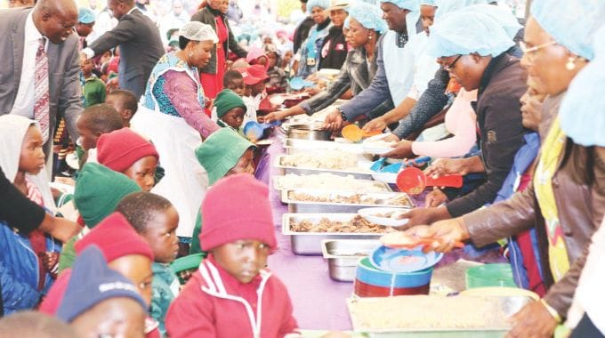 Schoolchildren receive food during one of the countless school feeding programmes organised by First Lady Dr Auxillia Mnangagwa around the country