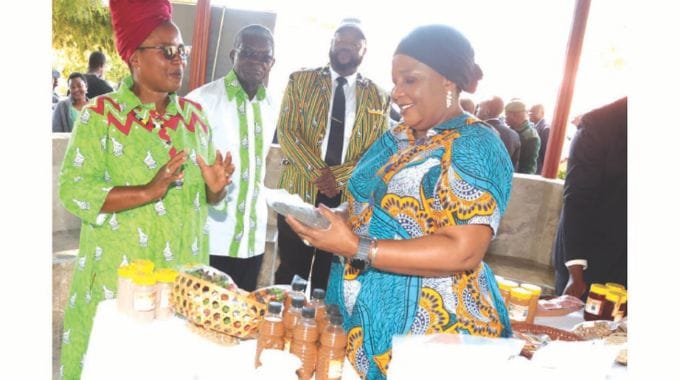 First Lady Dr Auxillia Mnangagwa admires the value added traditional grains and traditional fruits made into various products and juices while host farmers Mr and Mrs Taranhike and Minister of State and Devolution for Manicaland Advocate Misheck Mugadza look on during the launch of national Agro-Tourism4she in Manicaland yesterday