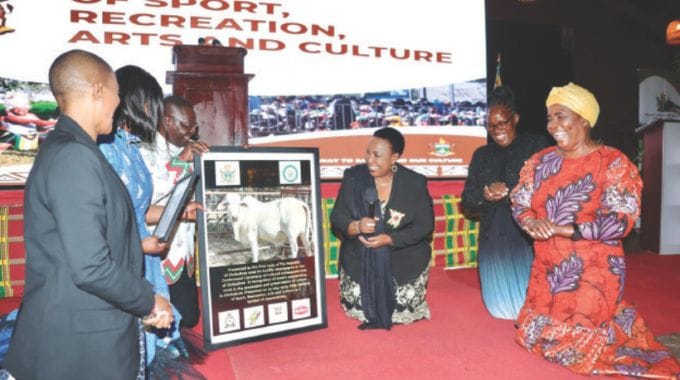 Sport, Recreation, Arts and Culture Minister Lt Gen (Rtd) Ambassador Anselem Nhamo Sanyatwe hands over the picture of the Heifer gifted to First Lady Dr Auxillia Mnangagwa for her sterling work in promoting Zimbabwe’s culture and heritage while Minister Barbra Rwodzi, Deputy Minister Emily Jesaya and traditional chief’s wives Mrs Charumbira and Mrs Seke help her to thank during the conferment of Ambassadorial role at the Heritage Museum in Harare