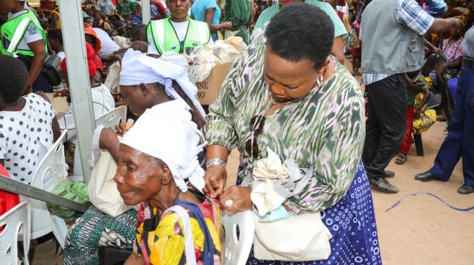 First Lady Dr Auxillia Mnangagwa hands out toiletries to an elderly woman, whom she also helps zip up her dress