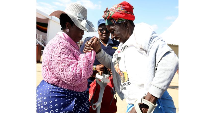 First Lady Dr Auxillia Mnangagwa assists an elderly woman who is struggling to stand during a highly interactive engagement on family unity at Mega Grounds in Stoneridge, Harare.