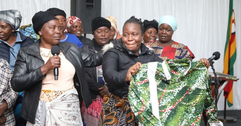 Mrs Charity Mangena helps a woman transform her shirt into a doek, illustrating that virtually any piece of cloth can be used as a doek.
