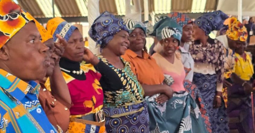 Elderly women proudly display the doeks and zambias they received from the First Lady