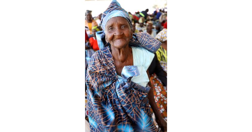 An elderly woman proudly dons a doek and zambia she received from First Lady in Binga